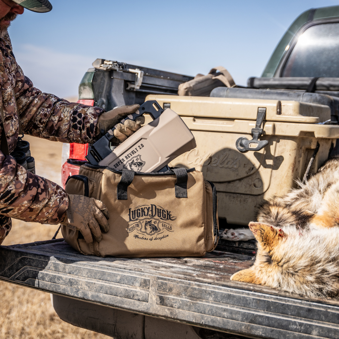 Person in camouflage loading a Lucky Duck E-Caller Super Revolt 2.0 in a bag into a truck bed.