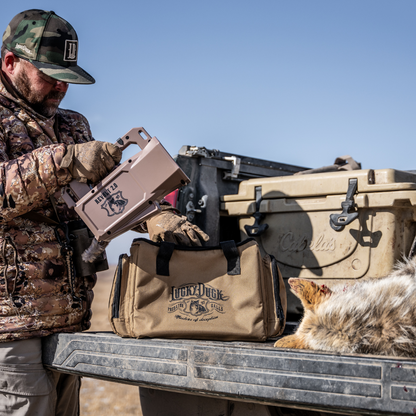 Man in camouflage gear with a cooler and E-Caller bag on a truck bed