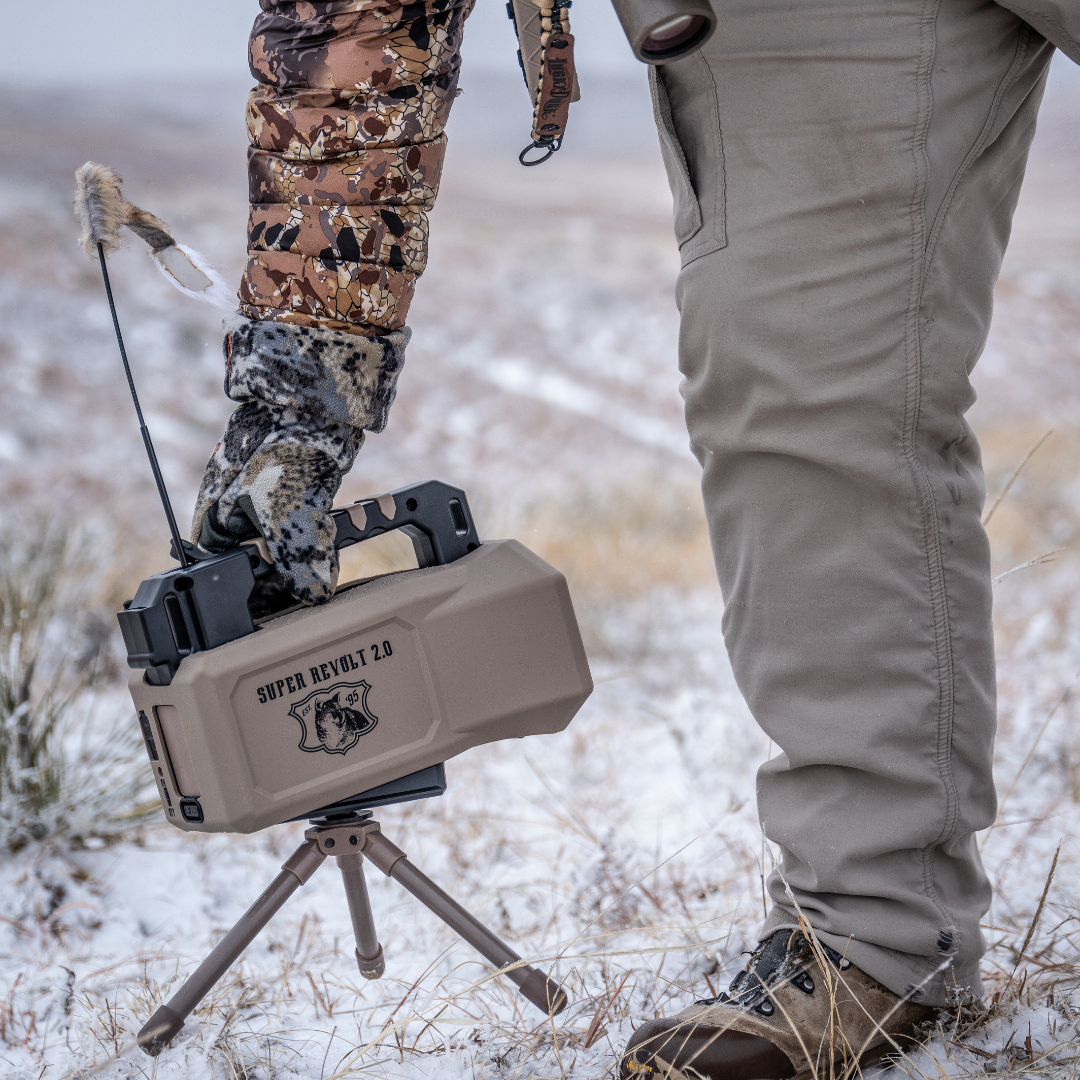 Hunting scene with a person in camouflage gear and a device labeled Lucky Duck Super Revolt 2.0 in a snowy landscape.
