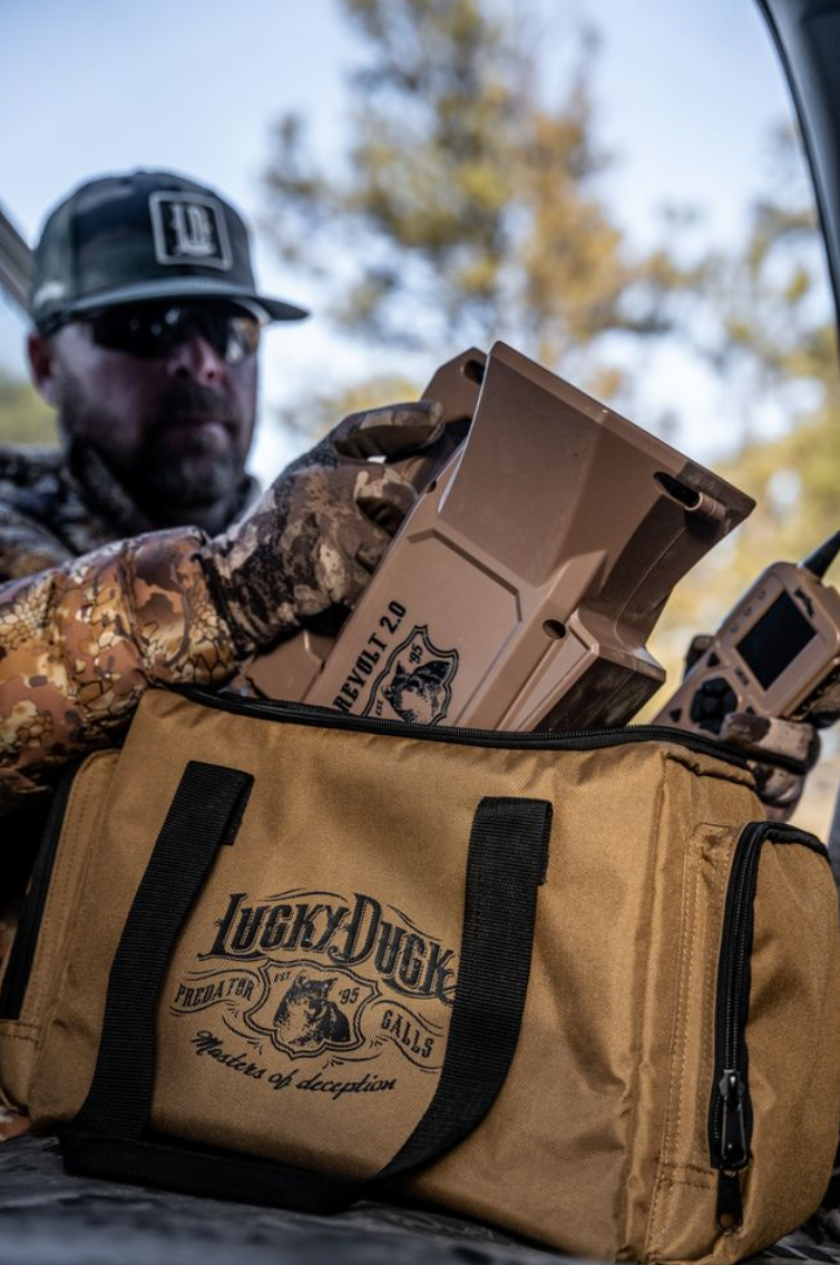 Person holding a 'Lucky Duck' bag with hunting gear in a forest setting