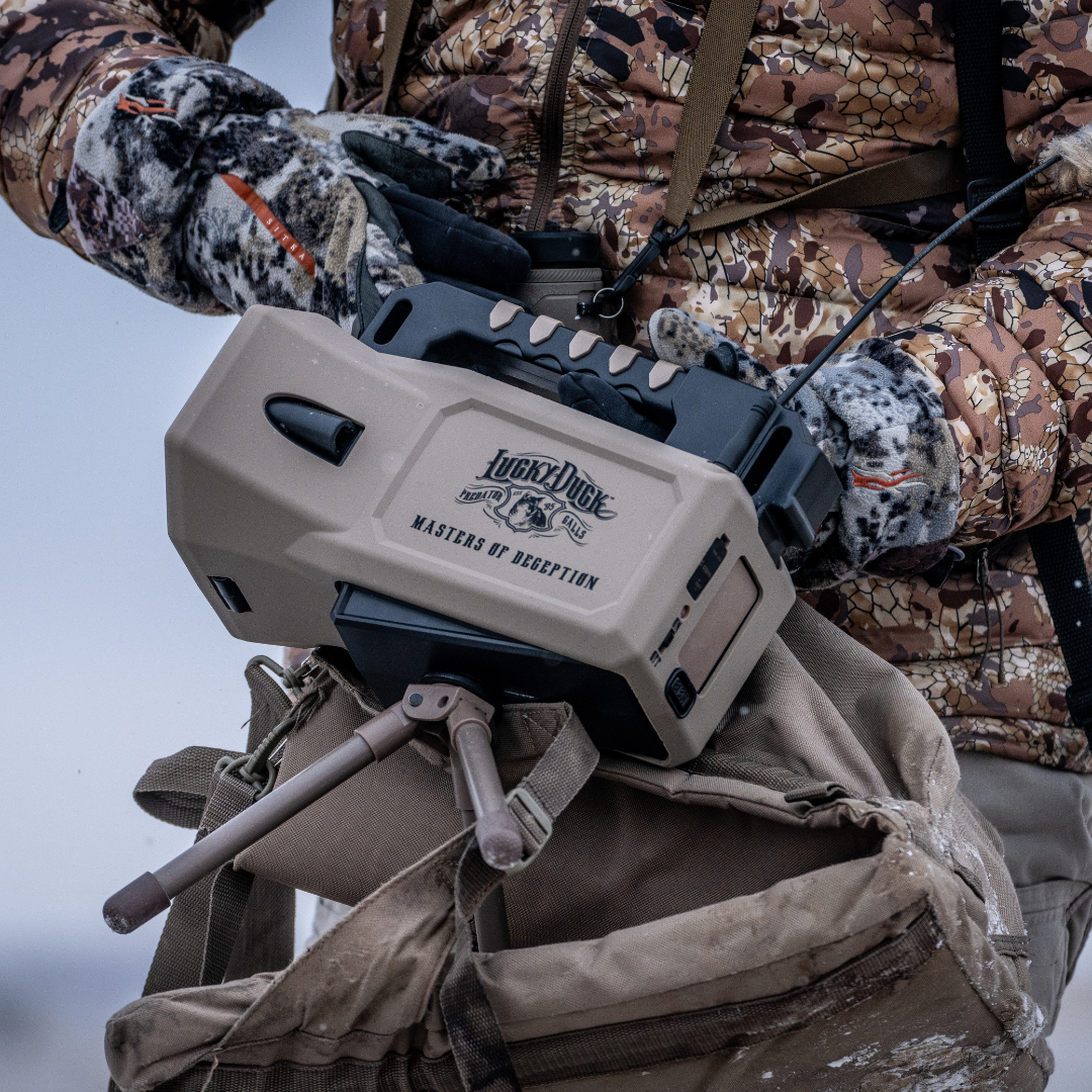 Person in camouflage gear holding a Lucky Duck Super REVOLT 2.0 E-Caller on a hunt.